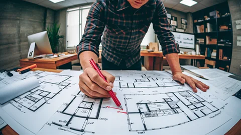 Drawing review with marked-up architectural plans on a desk